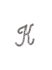 Silver brooch with letter 'K' design on a white background