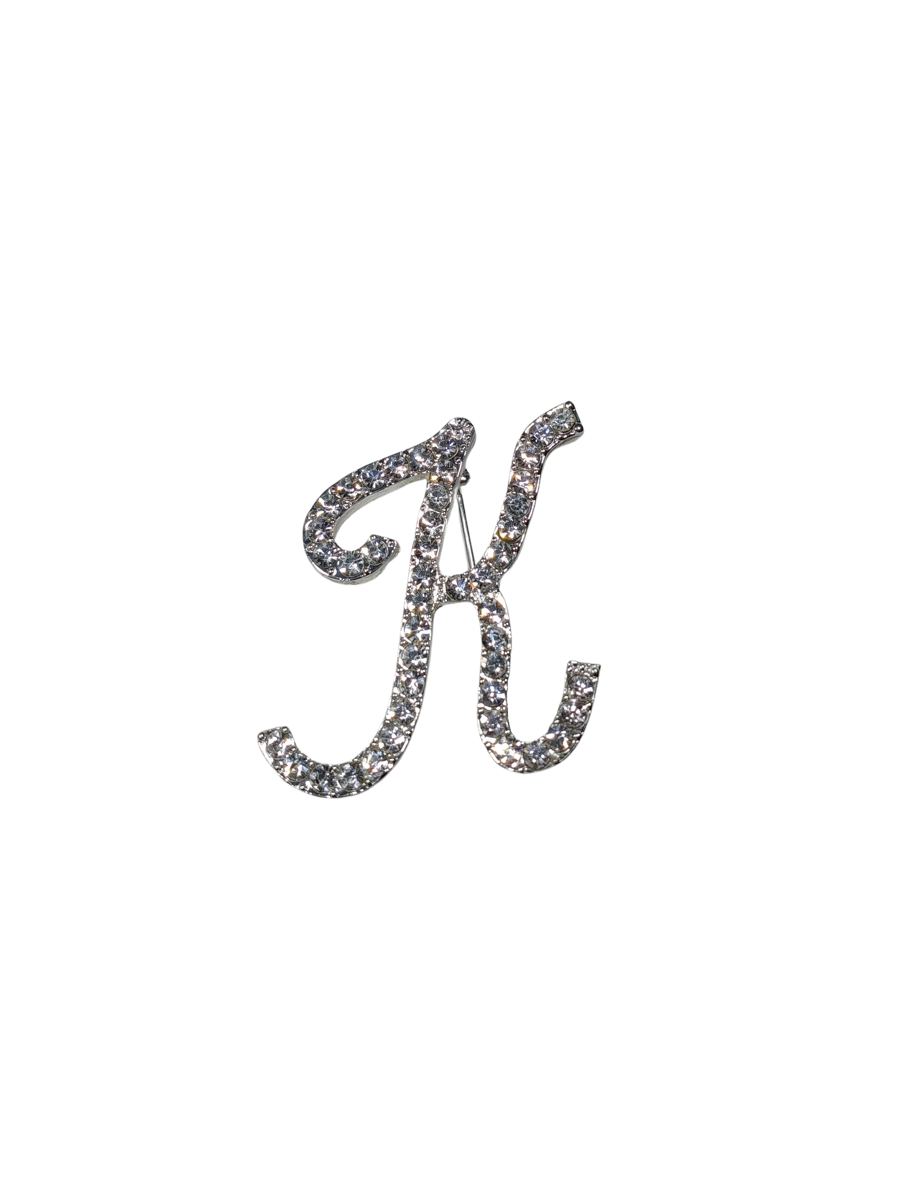 Silver brooch with letter 'K' design on a white background